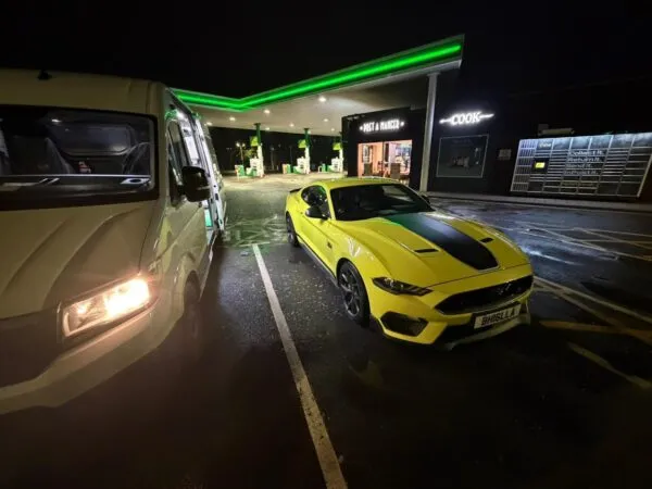 Yellow Ford Mustang parked beside a mobile tyre service van at a petrol station during a nighttime tyre callout.