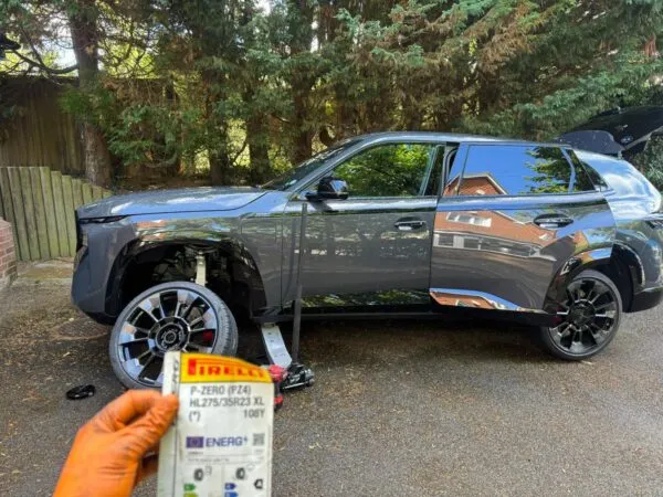 Mobile tyre fitting in progress on a grey SUV, with a Pirelli tyre label shown in the foreground.